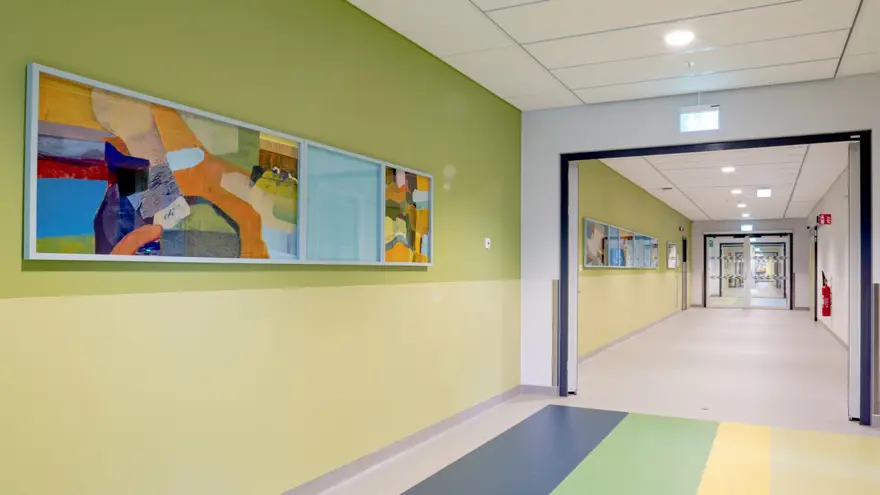 Målningar placerade på en gulgrön vägg i en korridor