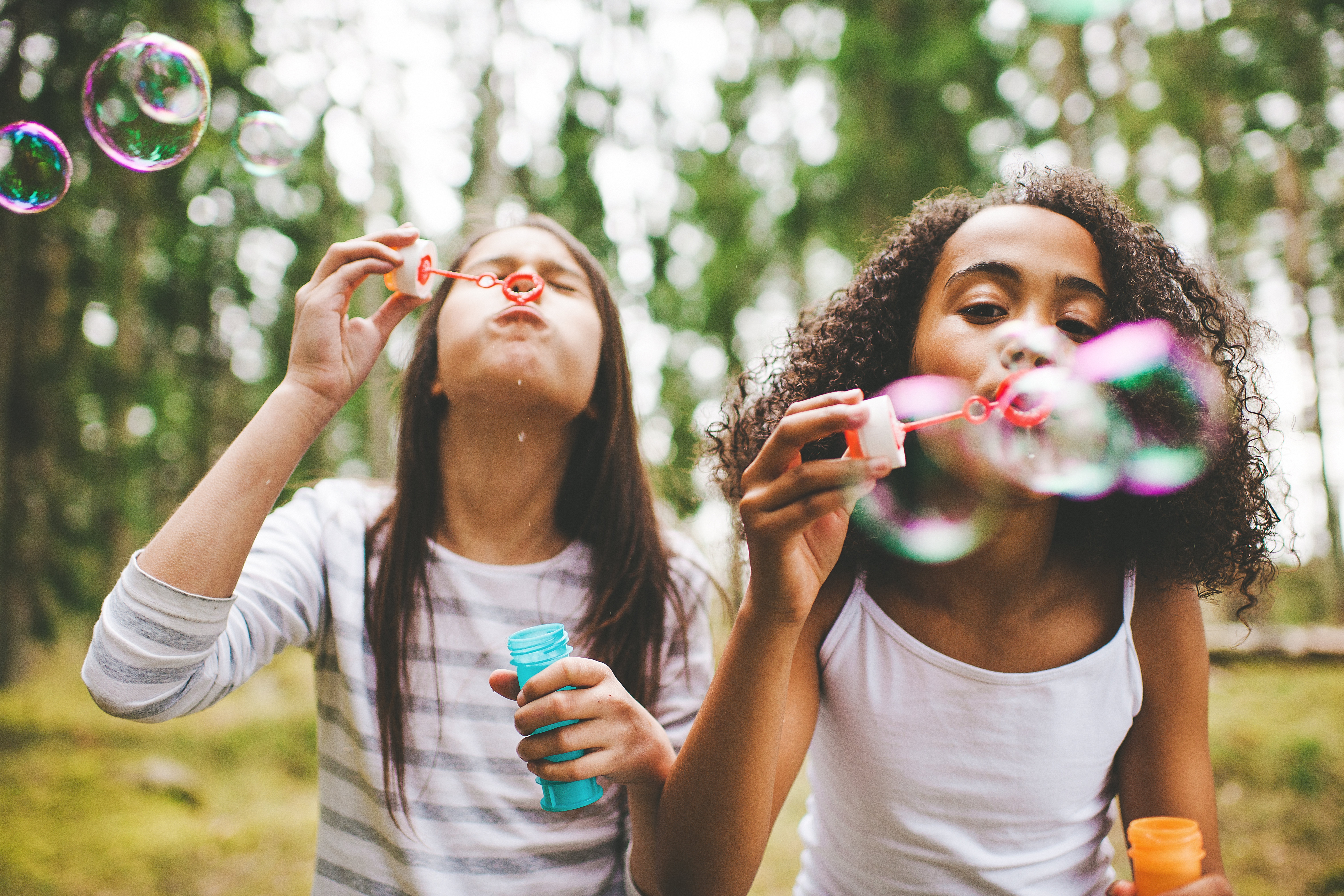 Cute girls blowing bubbles outdoors Bilder avsedda för att illustrera hållbarhetsmål Avsedd för att illustrera hållbarhetsmål