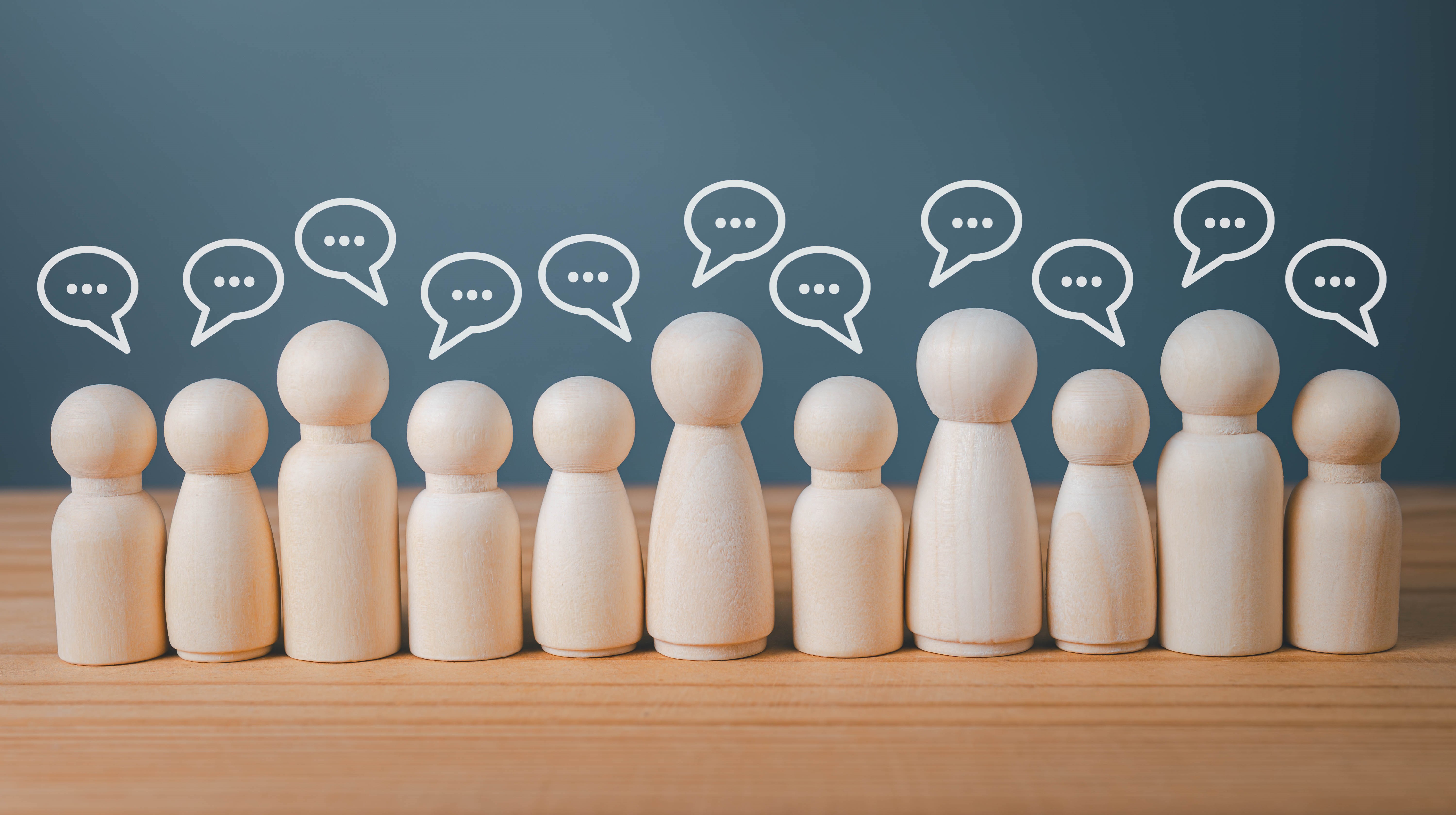 Elva trägubbar på rad med pratbubblor ovanför huvudena