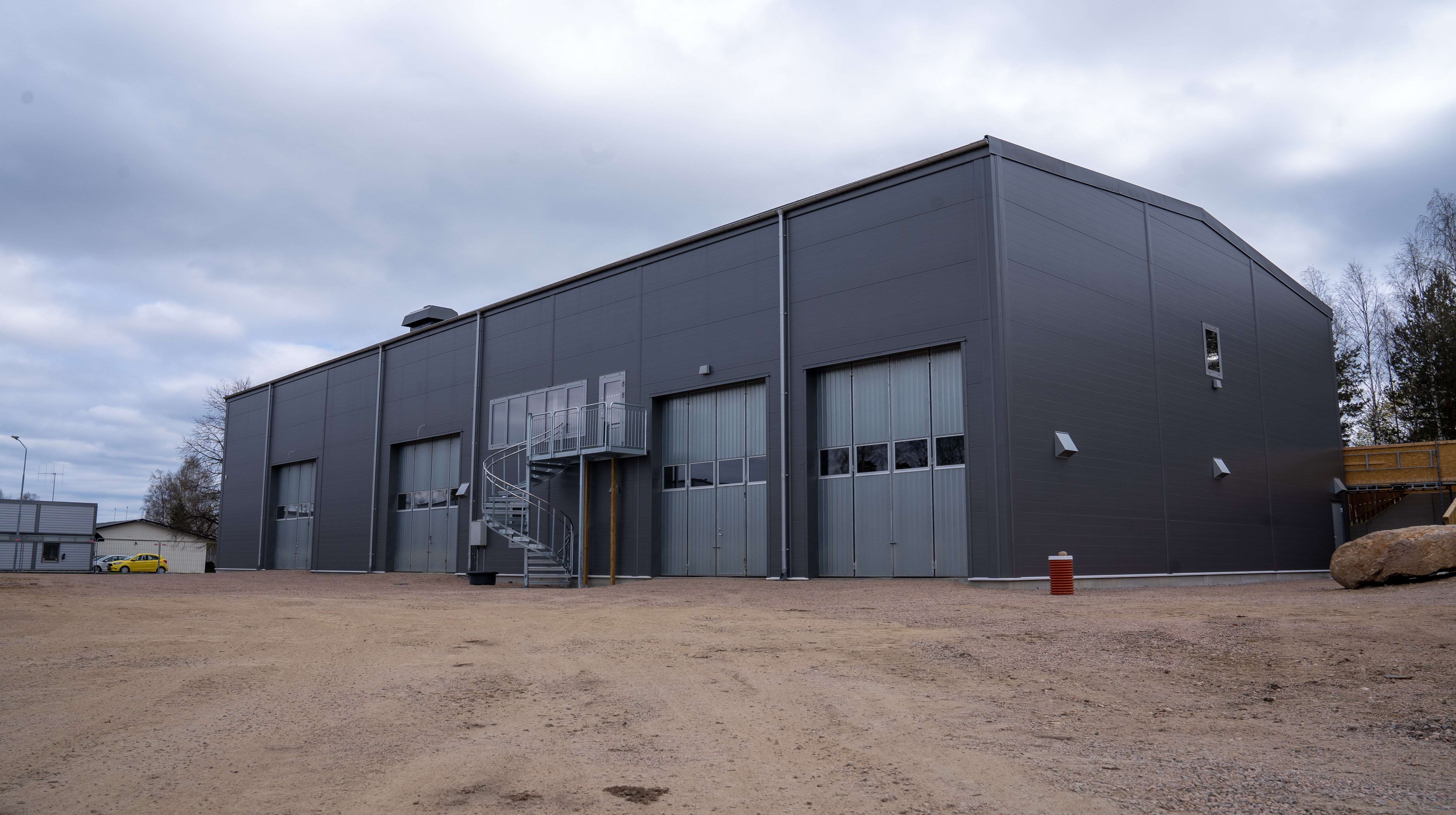 Grå maskinhall med grusplan framför
