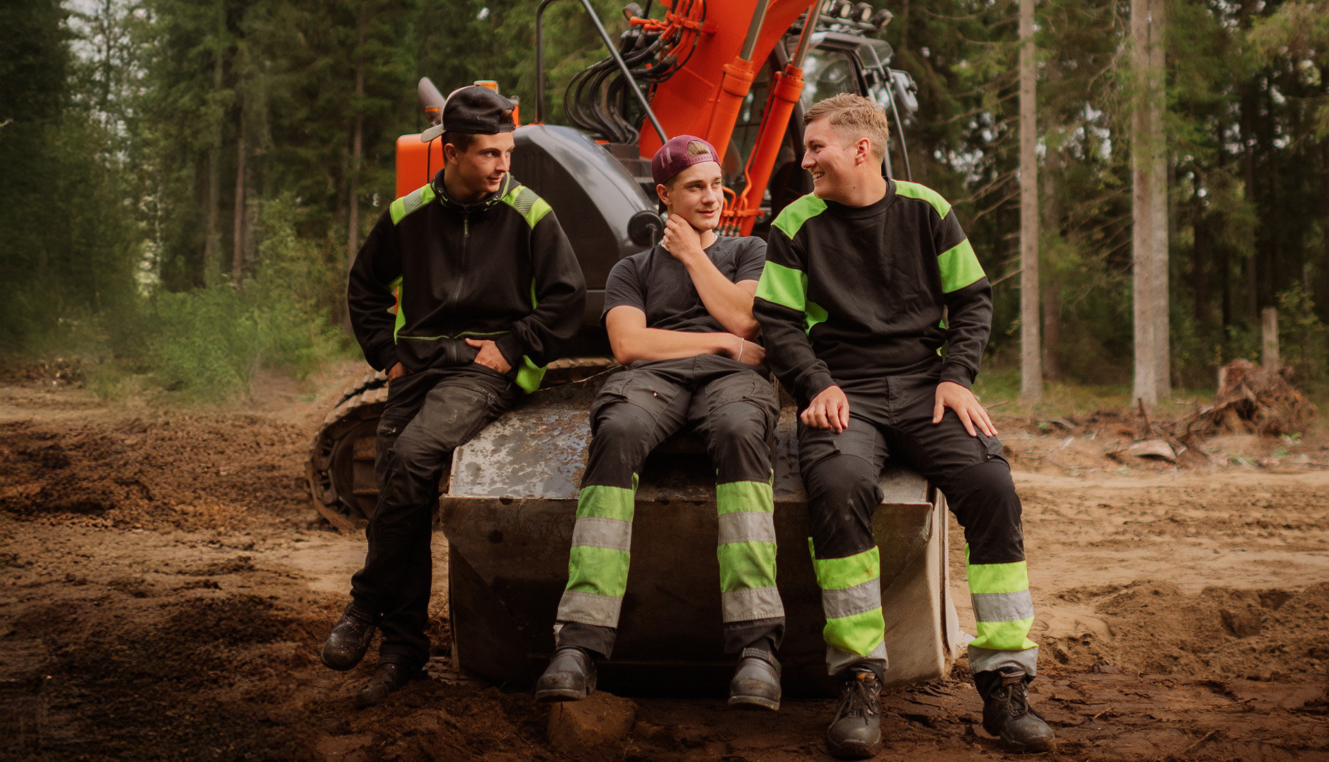 Tre elever sitter ned tillsammans på en grävskopa