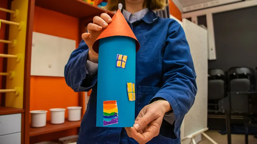 Ett blått muminhus i papper som någon har skapat på Bibblabbet. Rachel Barron håller fram det för kameran.