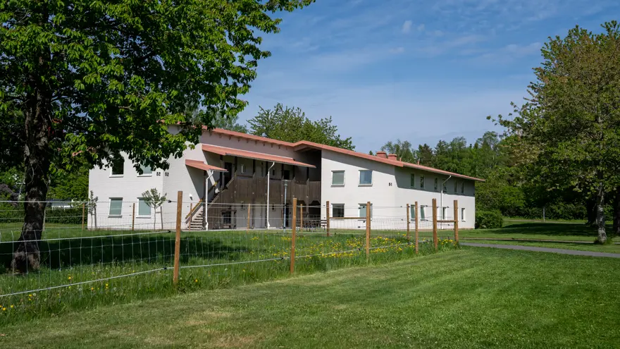 Tvåvånings-internathus omgivet av gräsmatta och lummiga träd