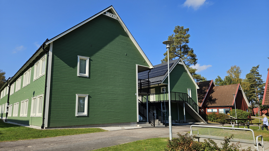 Svenljungas internat med två gröna tvåvåningsbyggnader i förgrunden och en röd byggnad bakom