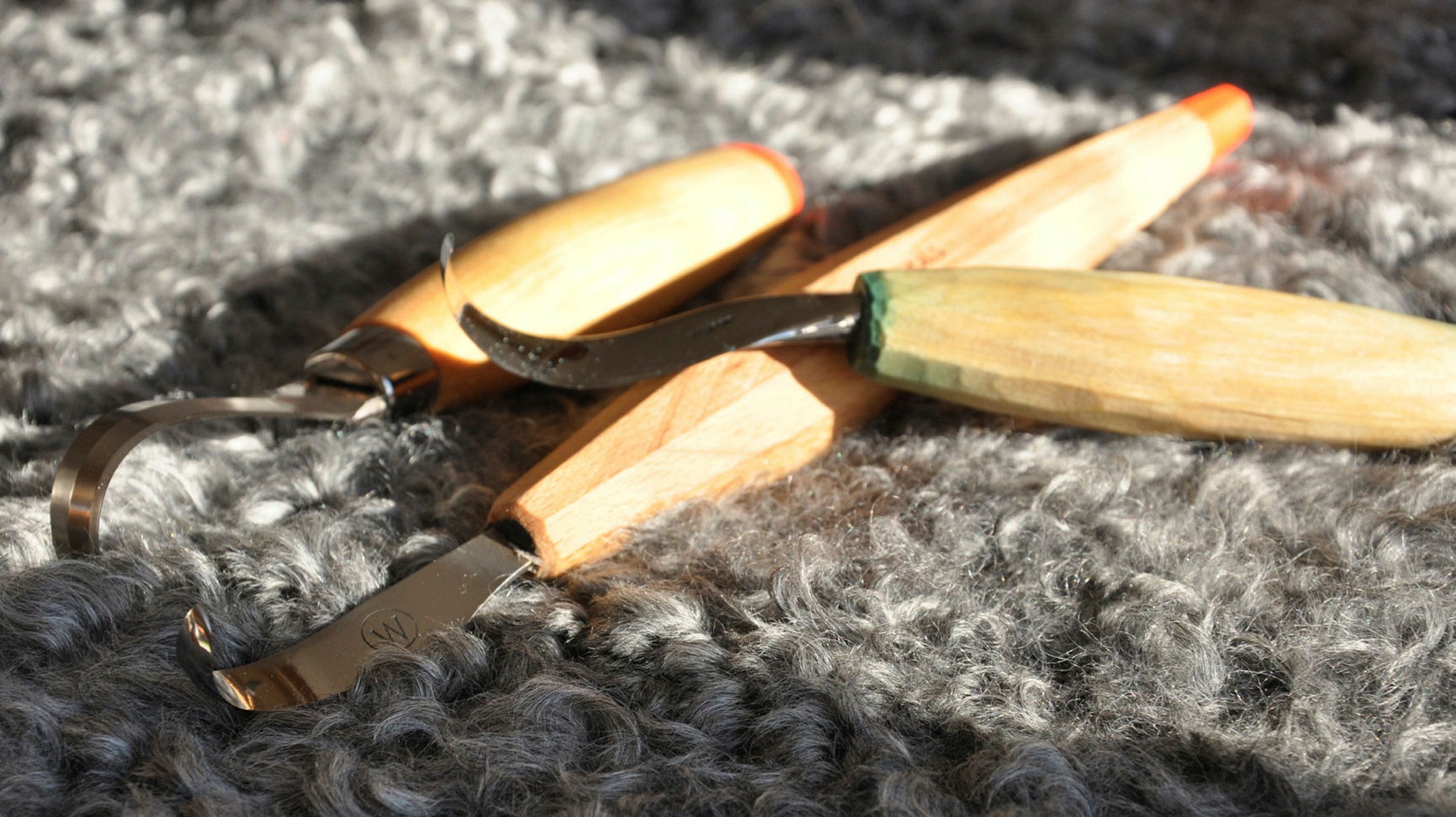 Tre skedknivar ligger på grå ull