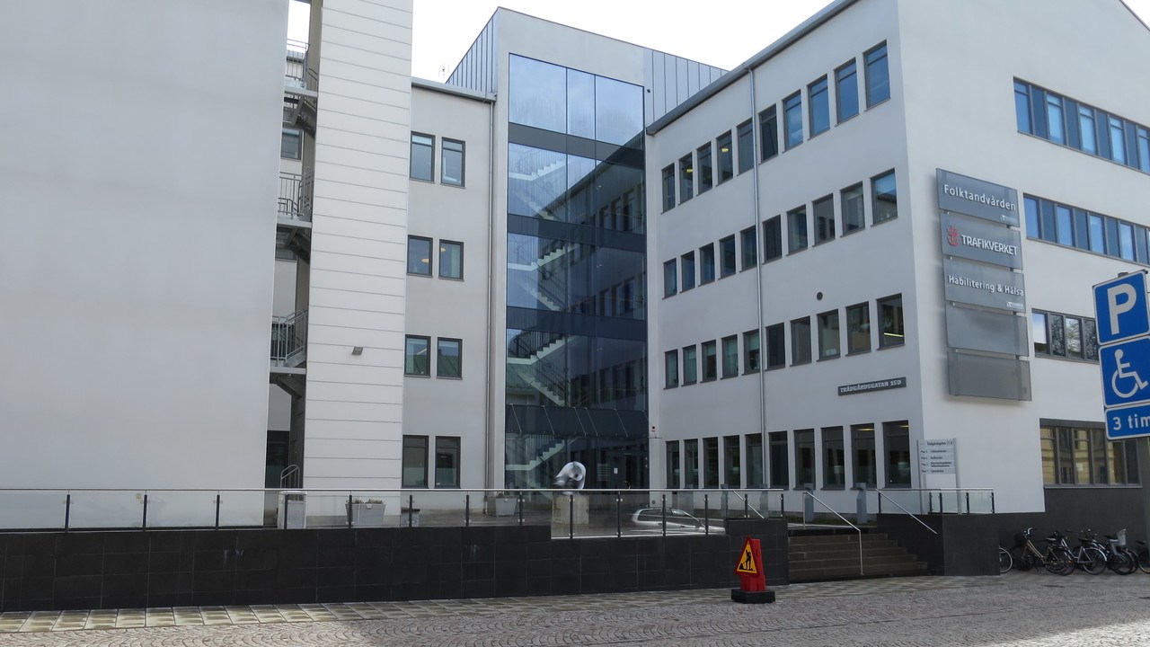 Vit byggnad med stort glasparti. 