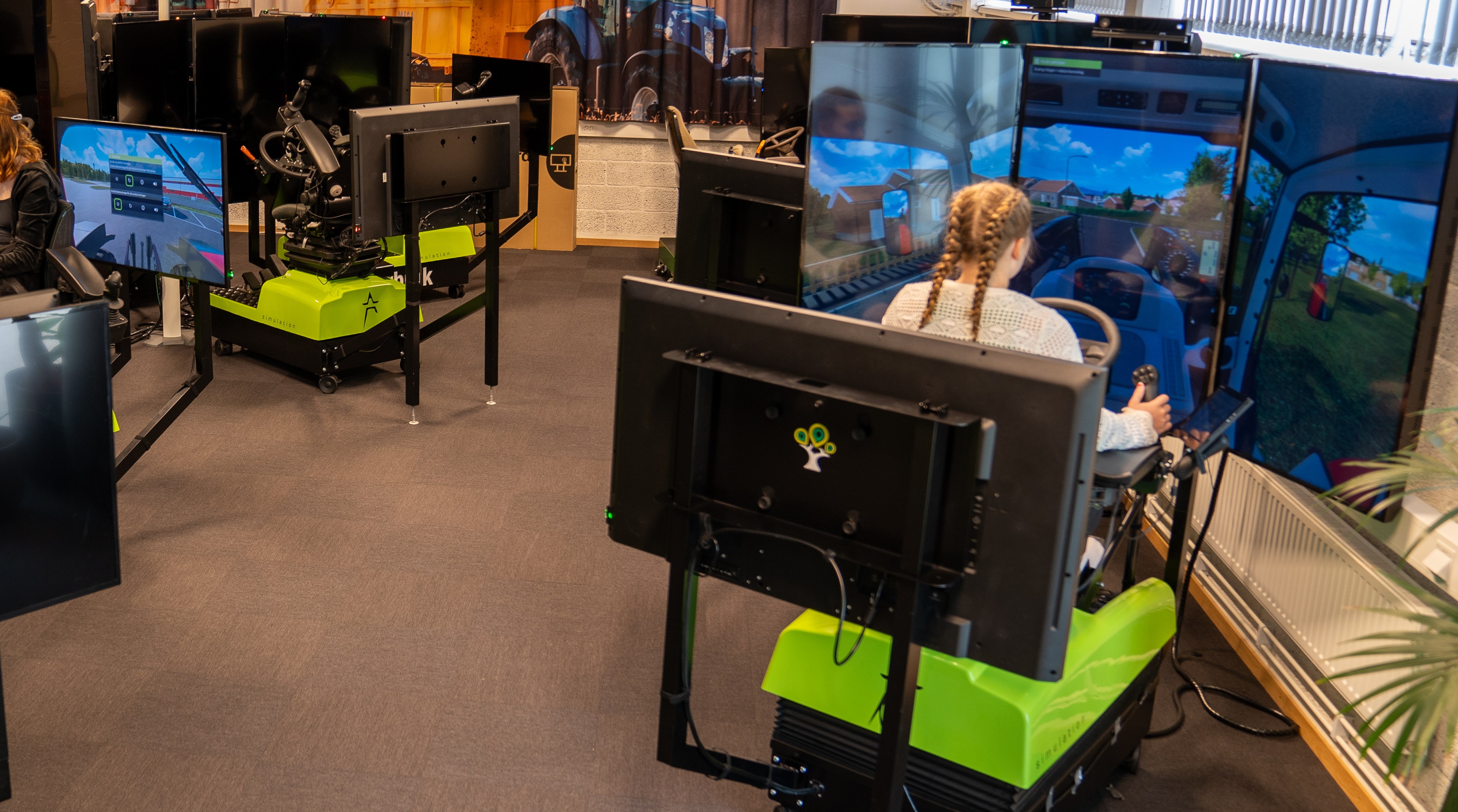 Elever sitter i simulatorer med skärmar och kör olika slags maskiner
