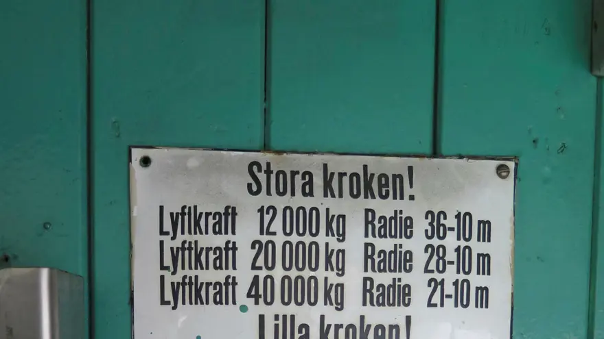 Skylt med viktangivelser och radie för stora och lilla kroken. Varningsskylt: När kranen är i drift skall 1. Kranjobben ställas in på 36 meters radie och parallellt med kranbanan. 2. Bromsarna dragas åt till sväng och jibb-maskinerna. 3. Rälsklammerna låsas fast. 4. Huvud ström brytaren à portalen brytes.