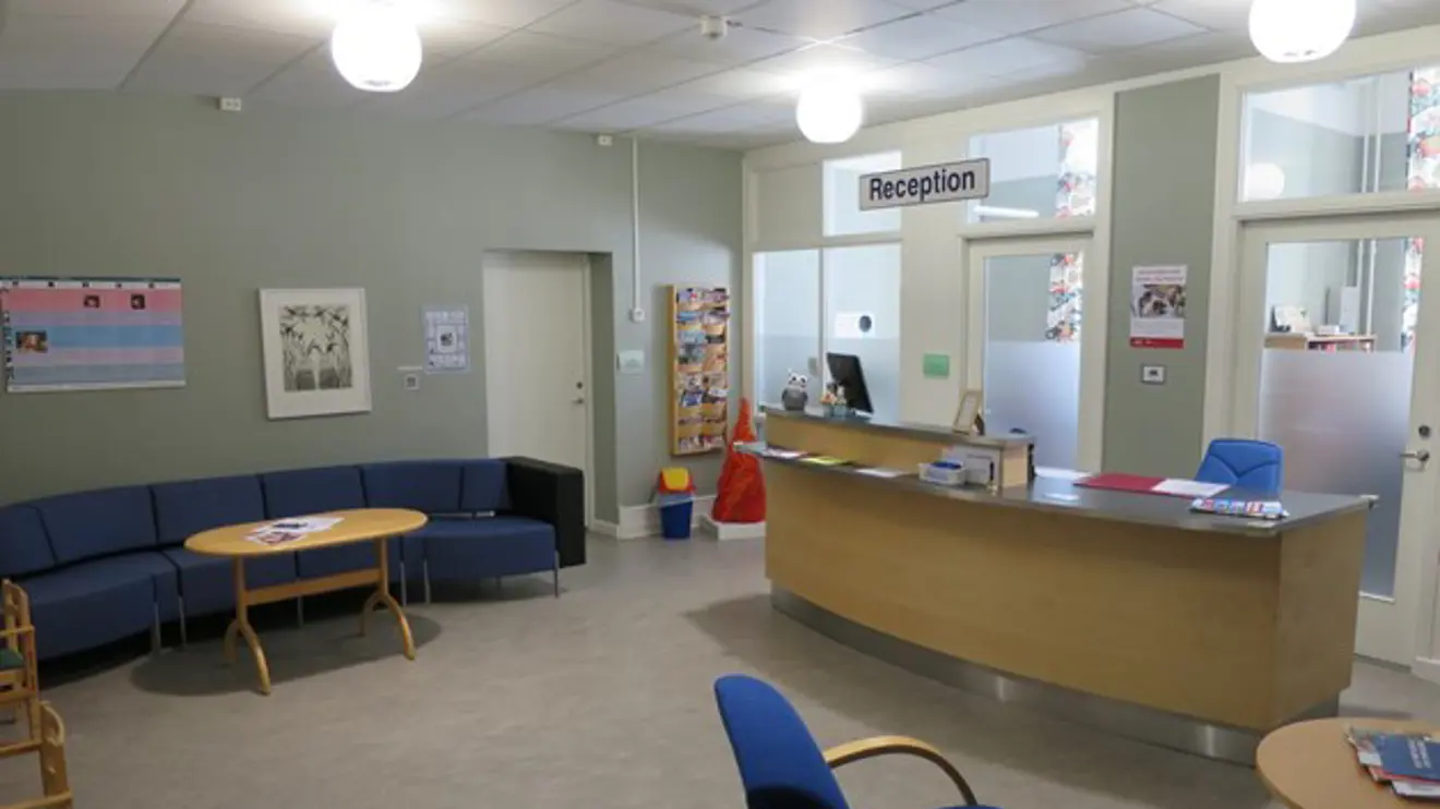 Väntrum med receptionsdisk som är lite svängd och soffa.